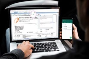 laptop screen showing invoice document, and a mobile showing whatsapp App